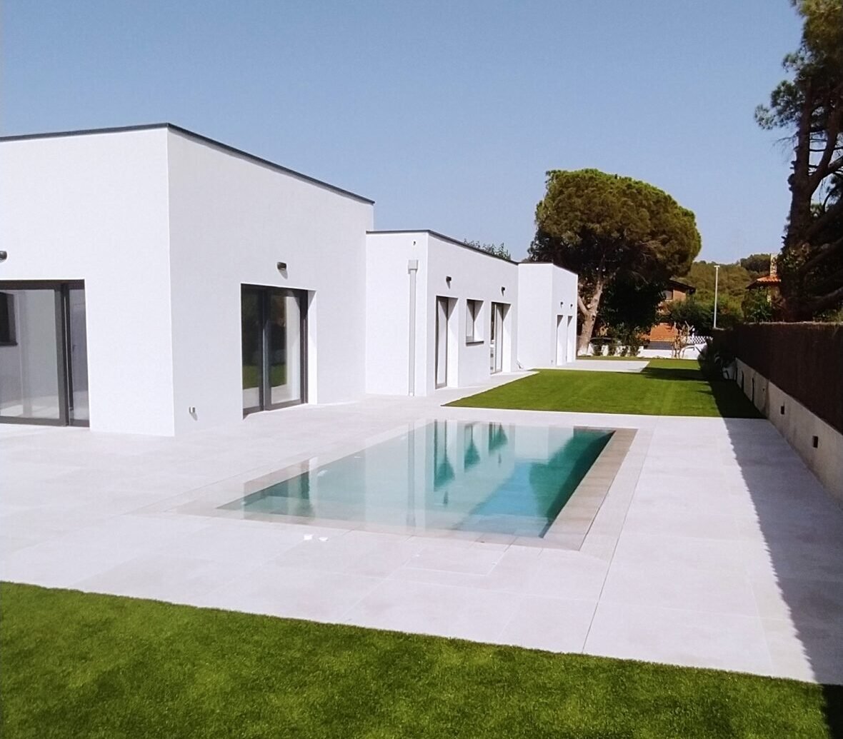 casa moderna blanca con piscina al aire libre y jardín, diseño minimalista y eficiente energéticamente.