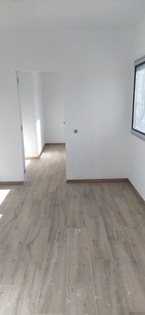 Pasillo interior con suelo laminado y paredes blancas en casa prefabricada moderna