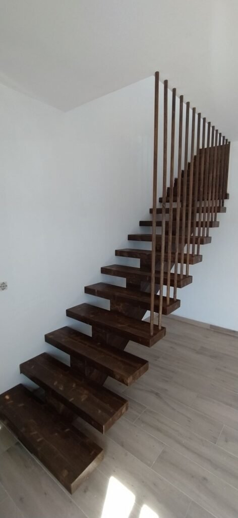 Escalera interior moderna con peldaños de madera y barandilla en casa prefabricada