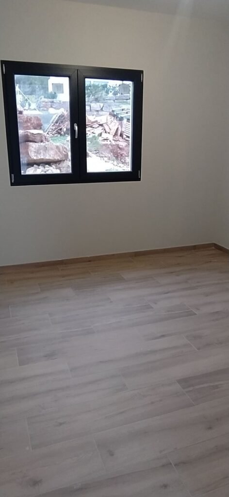 Dormitorio vacío en casa prefabricada con suelo laminado y ventana exterior