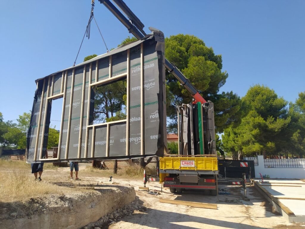 Montaje con grúa de panel de pared para casa prefabricada durante la fase de estructura y cerramiento exterior