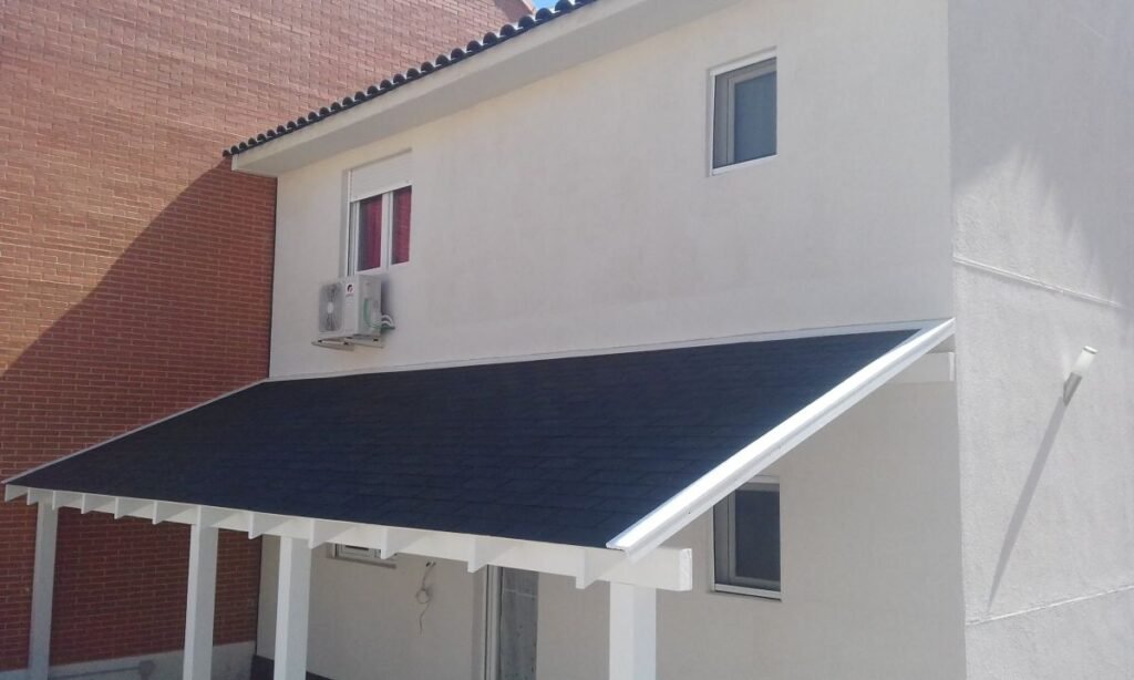 Detalle de porche cubierto en vivienda prefabricada de dos plantas con estructura de madera y cubierta inclinada