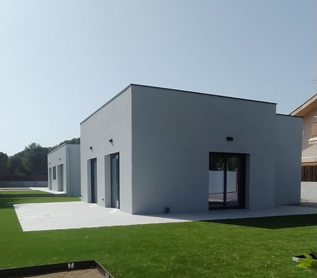 Imagen exterior lateral de una casa prefabricada moderna con piscina y jardín, diseñada con líneas rectas y acabados contemporáneos. Vivienda construida por Casas a Medida Pro, pensada para ofrecer eficiencia energética, confort y una conexión directa entre interior y exterior